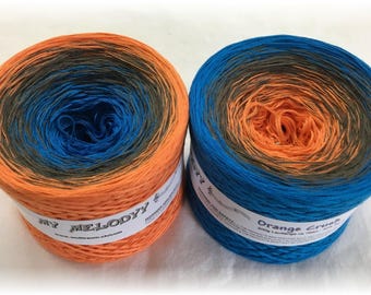 May include: Two skeins of yarn, one orange, blue and black ombre and the other blue, orange and black ombre. The skeins are labelled "My Melody" and "Orange Crush".