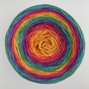 May include: A skein of rainbow colored yarn wound into a ball. The yarn is a mix of green, blue, purple, pink, orange, and yellow.