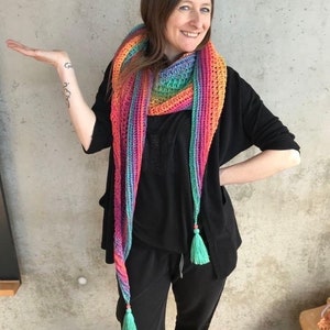 May include: A long, colorful crochet scarf with a rainbow gradient of pink, orange, yellow, green, blue, and purple. The scarf has two long tassels at the ends, which are a bright turquoise color.