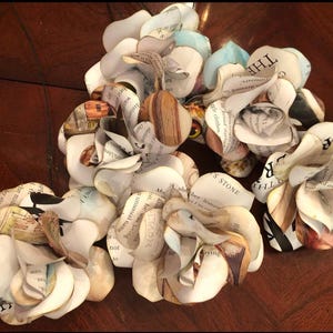 May include: A bouquet of paper flowers made from book pages. The flowers are white and have a vintage look. The text on the pages is visible, including the words "The Stone" and "The Clottin".