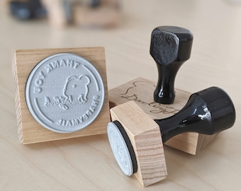 May include: Three wooden stamp blocks with black handles. The first block has a grey rubber stamp with the text "JOY THANK YOU" and a small elephant design. The second block has a grey rubber stamp with the text "Darling". The third block has a grey rubber stamp with the text "Thank You".