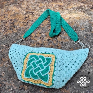 May include: A crocheted light blue bag with a green Celtic knot design. The bag has a green adjustable strap and a silver clasp. The bag is on a brown and gray textured surface. The text "Celtic Knot Crochet" is visible in the lower right corner of the image.