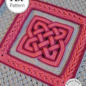 May include: Close-up of a crocheted blanket with a Celtic knot design. The blanket features a central knot in shades of pink, framed by a square border and a textured gray background. The words "PDF Pattern" are in a white circle.