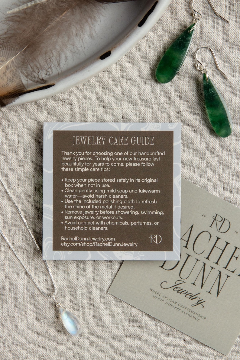 May include: An image featuring a silver necklace with a teardrop-shaped pendant, green jade earrings, and a jewelry care guide. The guide provides care tips. A business card with the text "Rachel Dunn Jewelry" is also visible.