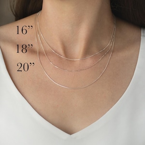 May include: A close-up of three silver chain necklaces of varying lengths: 16", 18", and 20". The text "Chain Lengths" is displayed below the necklaces. The chains are shown against a white background.