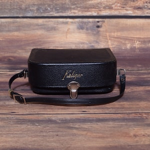 May include: A black leather camera case with a gold Kaligar logo and a black adjustable strap.