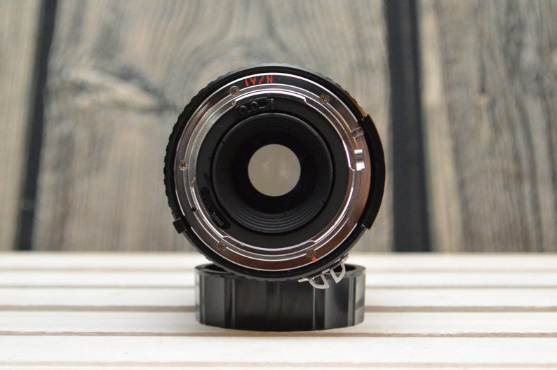 May include: Close-up of a black camera lens with a silver ring and the text "N/A1" printed on it.
