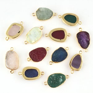 Puede incluir: Una colección de conectores de piedras preciosas en varias formas y colores, incluyendo rosa, verde, azul y morado. Cada piedra está engastada en un bisel dorado con pequeños bucles para sujetar a la joyería. Las piedras preciosas tienen una textura rugosa y natural.