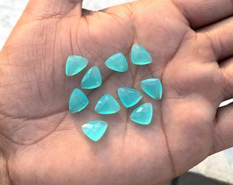 May include: A collection of 12 turquoise triangle-shaped gemstones. The gemstones are faceted and have a translucent appearance.