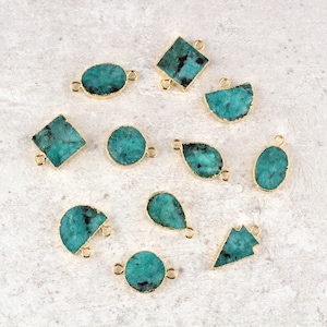 Könnte beinhalten: Eine Sammlung von türkisfarbenen Edelsteinanhängern in verschiedenen Formen, darunter oval, tropfenförmig und quadratisch. Jeder Anhänger hat eine goldfarbene Lünette und kleine Schlaufen zum Befestigen an Schmuck. Die Edelsteine haben ein natürliches, strukturiertes Aussehen.