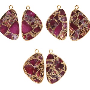 May include: Six gold-tone pendant charms with a red and gold marbled design. The charms are shaped like a teardrop with a loop at the top for attaching to a necklace or bracelet.