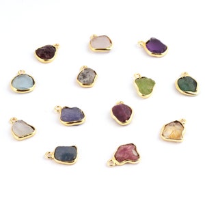 May include: Assortment of 12 gold-plated gemstone pendants with raw, irregular shapes. The gemstones are in various colours, including blue, green, purple, pink, and brown.