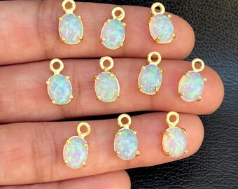 May include: Ten gold-tone oval-shaped charms with white opal stones. Each charm has a small loop at the top for attaching to jewelry.