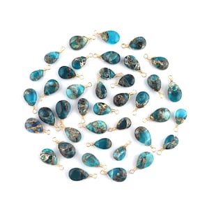 Puede incluir: Una colección de 30 colgantes de piedra turquesa azul en forma de lágrima con envolturas de alambre dorado. Cada colgante tiene un pequeño bucle para sujetarlo a joyas.