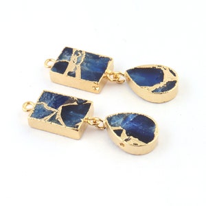 May include: A pair of gold-plated earrings with blue agate stone drops. The earrings feature a rectangular stone with a gold-plated frame and a teardrop-shaped stone with a gold-plated frame.