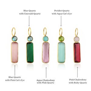 Op de afbeelding: Vijf goudkleurige hangers, elk met een kleine ronde edelsteen boven een grotere rechthoekige edelsteen. De combinaties zijn gelabeld als Blue Quartz with Emerald Quartz, Peridot Quartz with Aqua Cat's Eye, Blue Quartz with Pink Cat's Eye, Aqua Chalcedony with Pink Quartz en Pink Chalcedony with Ruby Quartz.