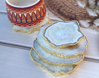 May include: Set of four white agate coasters with gold trim. The coasters are stacked on top of each other.