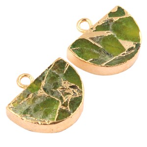 Puede incluir: Dos abalorios de metal dorado en forma de semicírculo. Cada abalorio está decorado con una piedra verde y dorada con un patrón de mármol.