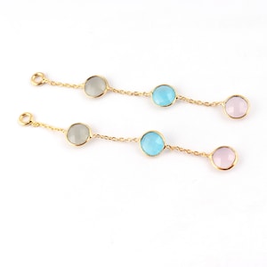 May include: Two gold chains with three gemstone beads each. The top chain has a gray bead, a light blue bead, and a pink bead. The bottom chain has a gray bead, a light blue bead, and a pink bead.