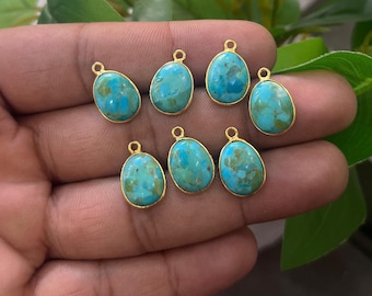 May include: Seven turquoise gemstone pendants with gold-colored bezels. The turquoise stones have a mottled blue-green appearance. Each pendant has a small loop at the top for attaching to a chain or other jewelry component.