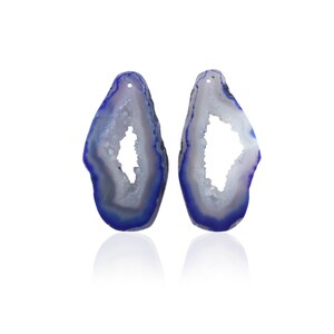 May include: Two blue and white agate slices with a natural crystal formation. The agate slices are oval shaped and have a hole drilled at the top.