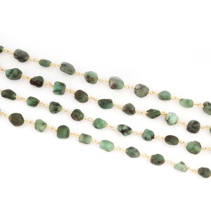 Peut inclure: Quatre rang&eacute;es de perles de pierres pr&eacute;cieuses vert &eacute;meraude sont enfil&eacute;es sur un fil dor&eacute; d&eacute;licat. Les perles sont de forme irr&eacute;guli&egrave;re et varient en nuances de vert, cr&eacute;ant une esth&eacute;tique naturelle. Le fond est blanc.