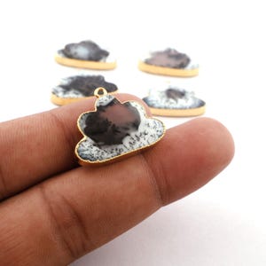 Könnte beinhalten: Ein Set aus fünf goldgerahmten, wolkenförmigen Anhängern mit dendritischem Achat-Stein. Der Achat ist eine Mischung aus weißen, schwarzen und braunen Farben.