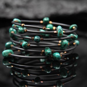 Könnte beinhalten: Ein schwarzes und grünes Armband mit mehreren Strängen schwarzer Schnur und grünen Edelsteinperlen.