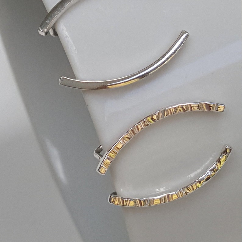 Puede incluir: Tres pendientes de aro de plata, dos son lisos y uno tiene un dise&ntilde;o texturizado.