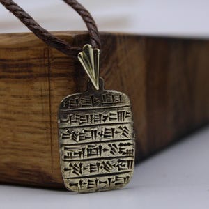 Un colgante en forma de tablilla de arcilla con escritura cuneiforme.