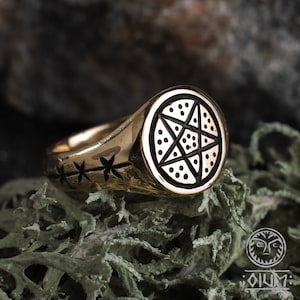 May include: A gold signet ring with a black pentagram design. The ring has a rounded top and a band with a repeating star pattern.