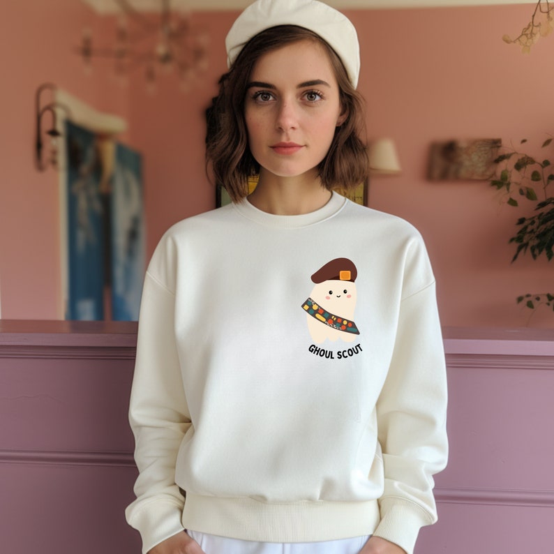May include: A white sweatshirt with a cartoon ghost wearing a scout uniform and the text "Ghoul Scout".