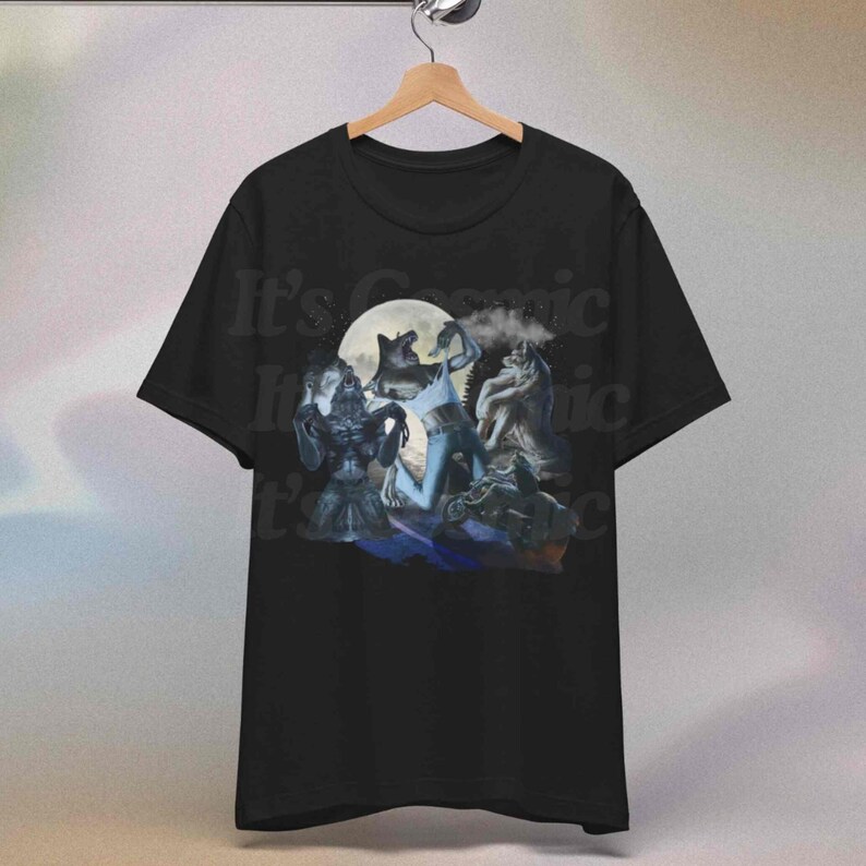May include: Black t-shirt with a graphic of werewolves under a full moon. The design includes the text "It's Cosmic". The artwork depicts several werewolf figures in a fantasy setting.