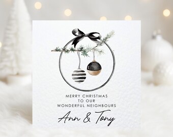 May include: A Christmas card with a watercolor design. The card features a black bow, a circular frame with two ornaments, and text that reads "Merry Christmas to our Wonderful Neighbours Ann & Tony."