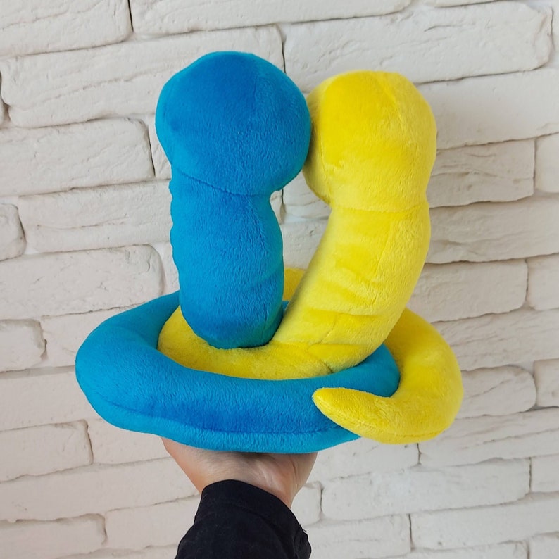 Pu&ograve; includere: Un giocattolo di peluche blu e giallo a forma di due serpenti intrecciati. Il giocattolo &egrave; realizzato in tessuto morbido e peloso e ha un design giocoso e fantasioso.