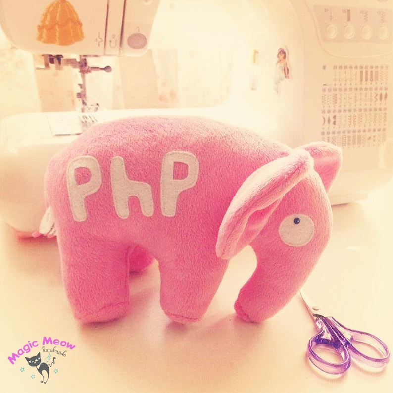 K&ouml;nnte beinhalten: Ein rosa Pl&uuml;sch-Elefantenspielzeug mit dem Wort "PHP" auf der Seite gestickt. Der Elefant hat ein wei&szlig;es Auge und ein langes, schlaffes Ohr.