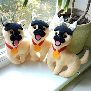 May include: Three plush toy dogs with black and white fur, wearing red collars with gold medallions. The dogs are sitting on a white surface.