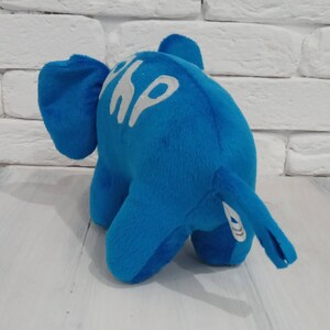 K&ouml;nnte beinhalten: Ein blauer Pl&uuml;sch-Elefantenspielzeug mit wei&szlig;er Aufschrift "Shop" an der Seite.