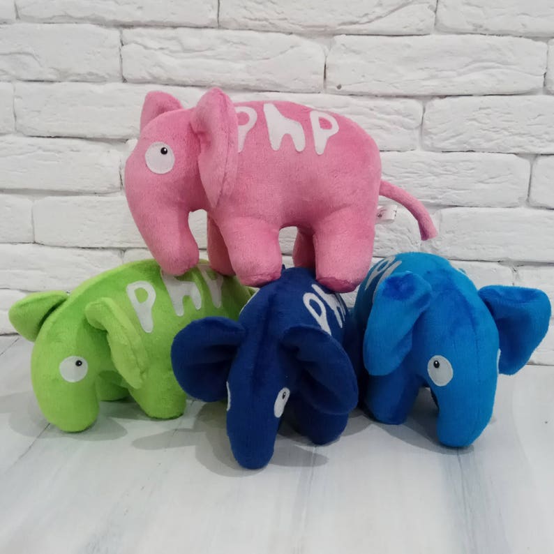 K&ouml;nnte beinhalten: Drei Pl&uuml;schelefanten, einer rosa, einer gr&uuml;n und einer blau. Jeder Elefant hat das Wort "PLAY" in wei&szlig;en Buchstaben darauf geschrieben.