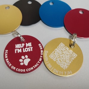 Può includere: Cinque etichette rotonde in metallo dorate, nere, blu, rosse e dorate con un codice QR. L'etichetta rossa ha il testo "HELP ME I'M LOST SCAN BACK OR CODE CONTACT MY OWNER" e un'impronta di zampa. L'etichetta dorata con il codice QR ha il testo "Smith | 56 | SK11 7JH".
