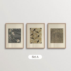Set of 3 vintage botanical and patterned wall art prints in natural oak frames with ivory borders. Featuring muted green floral illustrations, a beige organic textile-inspired pattern and an antique tree drawing, this coordinated gallery wall set brings earthy colors and layered vintage details to Japandi living rooms and eclectic interiors.