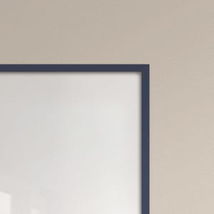May include: A corner view of a navy blue picture frame with a white interior. The frame is rectangular and has a clean, modern design. The background is a neutral beige color.