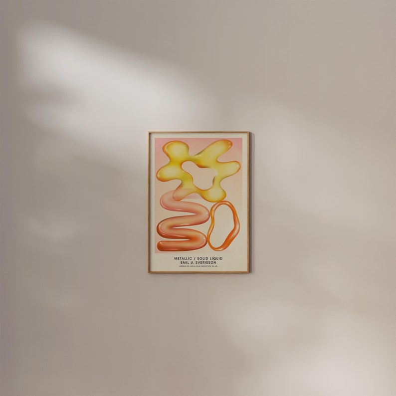 Puede incluir: Una impresi&oacute;n art&iacute;stica enmarcada con formas abstractas en tonos amarillos, naranjas y rosas. La obra de arte incluye el texto "METALLIC / SOLID LIQUID" y el nombre del artista. La impresi&oacute;n se muestra en un marco de madera marr&oacute;n claro.