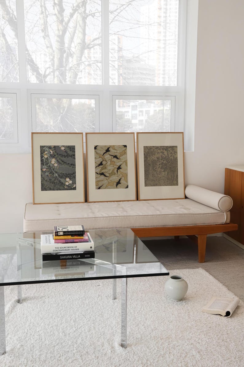 Set of three framed vintage wall art prints featuring floral textile, botanical leaf, and detailed forest designs, styled together in a bright neutral living room. Earthy gallery wall set for Japandi, organic modern, and eclectic interiors.