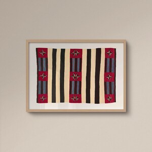 May include: A framed textile with a striped pattern. Alternating vertical stripes of black, cream, and red. The red stripes feature a cross-like design in the center. The textile is displayed in a light-colored wooden frame.