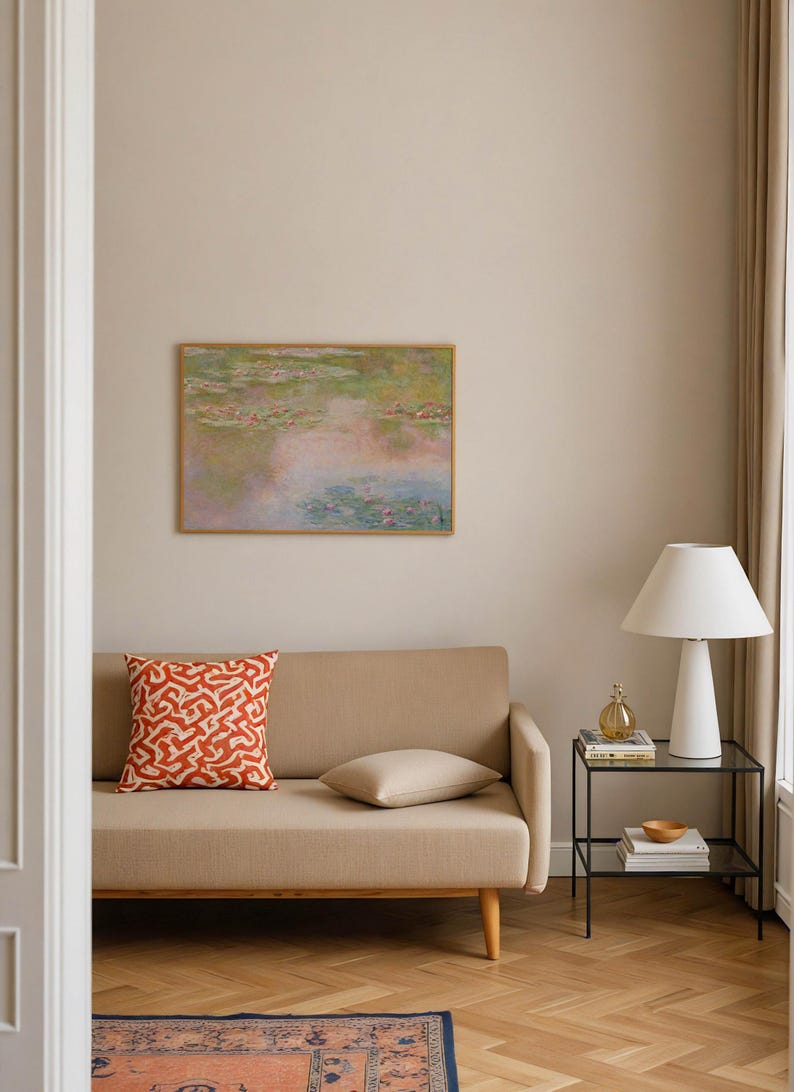 Pastel Monet Water Lilies wall art displayed above a beige sofa in a warm modern living room. Soft pink, sage green, lavender and blue tones create a dreamy impressionist landscape print for above sofa decor, bedroom or eclectic interiors.