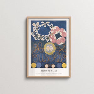 May include: A framed art print featuring Hilma af Klint's The Ten Largest, Childhood, No. 1, Group IV (1907). The composition displays a deep blue background with white floral motifs, pink circular patterns, orange cursive lines, and yellow circles.