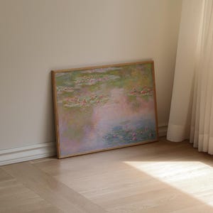 Puede incluir: Una impresi&oacute;n rectangular enmarcada que presenta una pintura de estilo impresionista de un estanque de nen&uacute;fares. La obra muestra tonos suaves de rosa, verde y azul, representando nen&uacute;fares flotantes y flores sobre una superficie de agua reflectante.