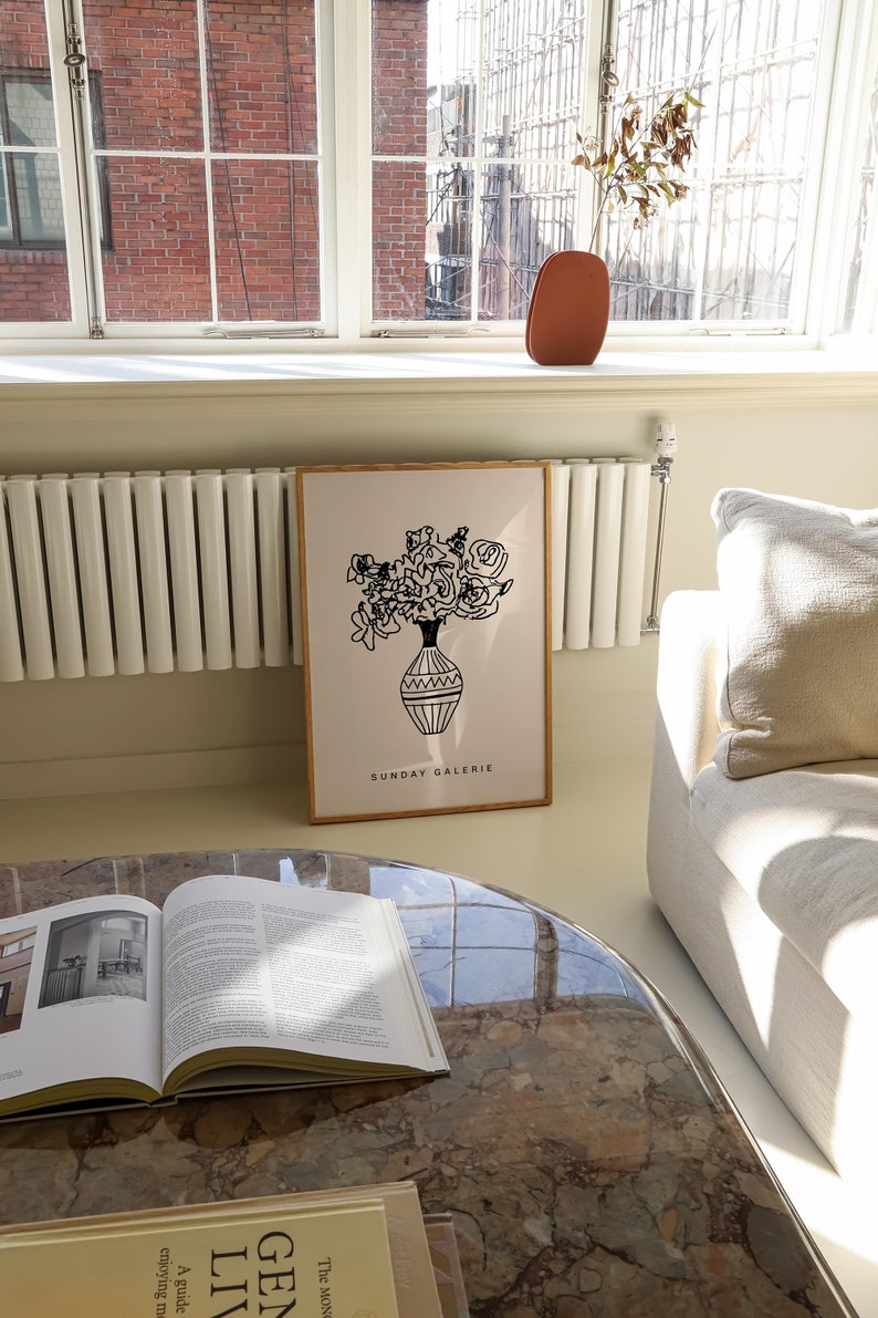 May include: A black and white line drawing of a bouquet of flowers in a vase. The drawing is on a white background with a wooden frame. The text "SUNDAY GALERIE" is printed below the drawing.