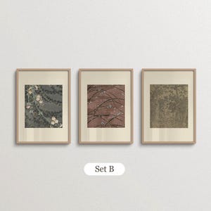 Neutral floral wall art set of 3 featuring delicate white blossoms, a vintage garden illustration and a detailed botanical tree print. Displayed in matching light wood frames with wide cream borders, this soft sage green and beige gallery arrangement suits cottagecore bedrooms, traditional interiors and nature-inspired home decor.